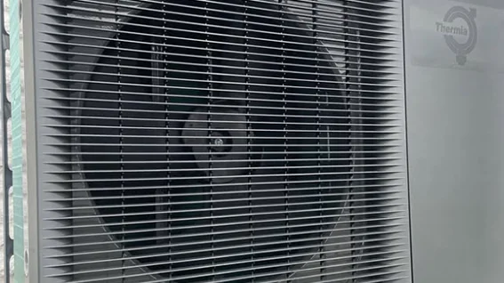 En grå/svart luftvärmepump som är placerad utanför huset